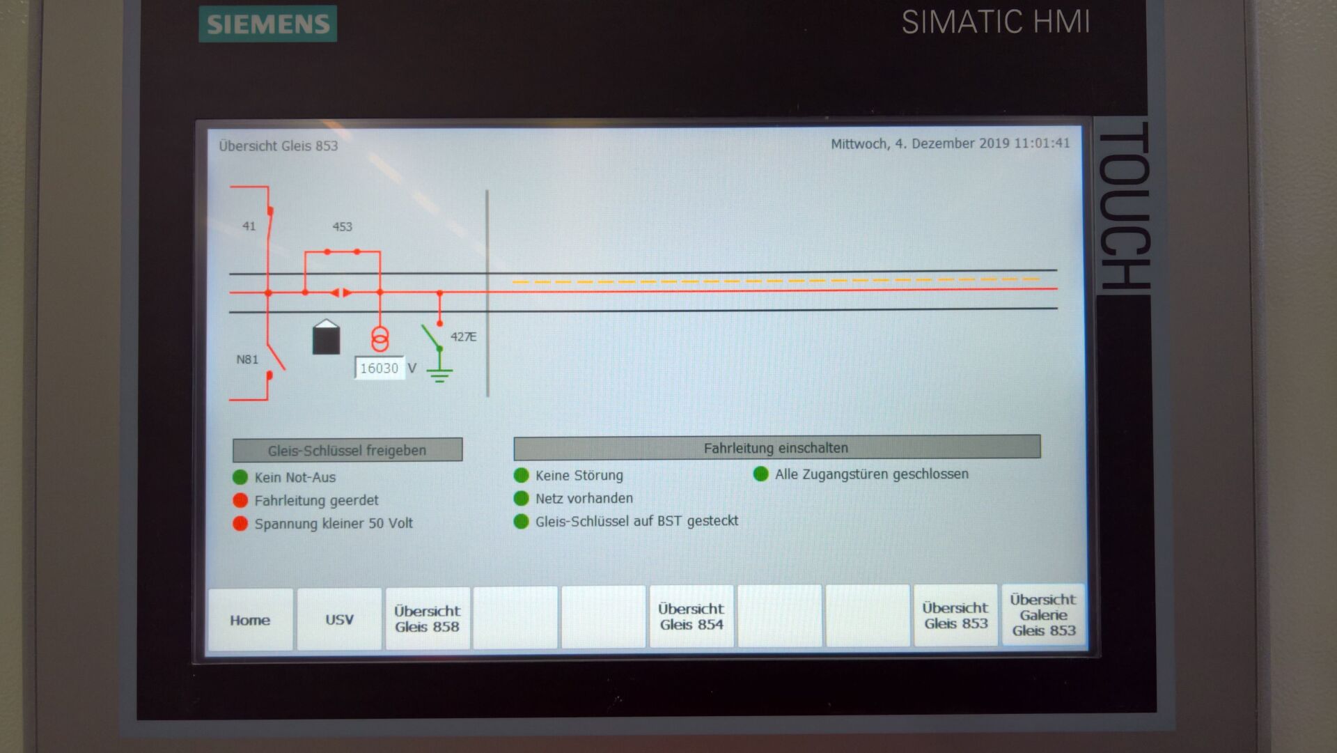 Ein Siemens SIMATIC HMI-Bildschirm zeigt eine Steuerschnittstelle mit verschiedenen Anzeigen, darunter Spannungspegel, Fehlerzustände und Betriebsstatus. Der Bildschirm zeigt ein Diagramm mit Linien, Textbeschriftungen und Schaltflächen zur Verwaltung verschiedener Abschnitte eines Systems.